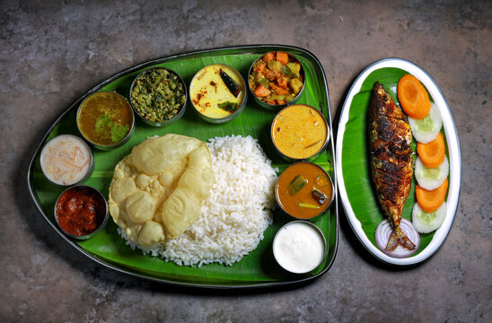 Delicious Indian Thali Meal with Rice, Fish Fry, Sides, and Fresh Vegetables

