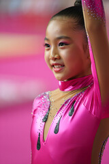 Young Gymnast Performing Under Bright Lights at a Competitive Event in a Vibrant Pink Outfit