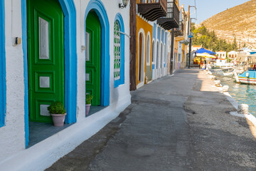 Obraz premium This photograph, which reflects the vibrant scenery of Meis Island, depicts a charming coastal street decorated with colorful doors and windows. Mediterranean architecture is an ideal choice for image