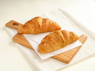 Golden Butter Croissants glistening with a light glaze on wooden cutting board side view of Flaky French Pastries