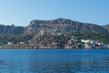 Bathed in Mediterranean sunlight, this photo captures the dramatic coastal cliffs and historic fortress ruins of Meis Island, Greece—ideal for visuals focused on travel, nature, and cultural heritage.
