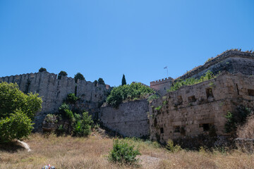 The timeless splendor of Rhodes Castle. Its medieval stone walls rise up under the bright sunlight,...