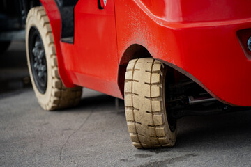 Close-up of red warehouse forklift with solid beige tires on concrete surface — durable...