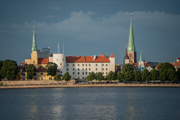 Fototapeta premium Historic Riga town skyline with church spires towers and castle reflecting in calm river water under clear blue sky on a sunny day urban architecture and cultural heritage cityscape