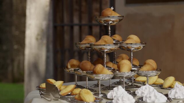 Rum baba and madeleines displayed on elegant silver trays. Action