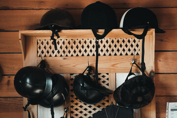 Assortment of Riding Helmets on a Wooden Rack with Wood Plank Background