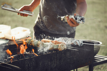 Grilling skewers with vegetables and meat over open flame, preparing food outdoors