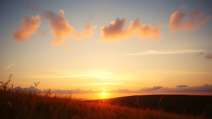 Fototapeta premium Sunset over a Low Hill with Subtle Clouds and Golden Grass