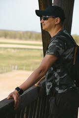 Man in Camouflage Shirt Observes Nature From Wooden Observation Deck