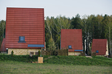 Red Tile Roofed Houses in a Rural Landscape with a Woven Fence and Verdant Meadow