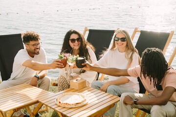 Friends toasting drinks at beach cafe