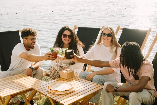 Friends toasting drinks at a lakeside cafe
