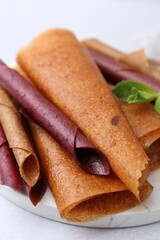 Delicious fruit leather rolls and mint on light table, closeup