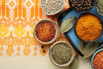 Many different aromatic spices in bowls on table with cloth, flat lay. Space for text