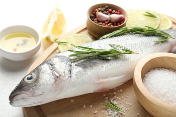 Fresh raw seabass with spices on white table, closeup. Fish and seafood delicacies