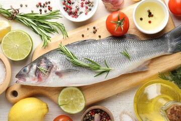 Fresh raw seabass with spices on white wooden table, flat lay. Fish and seafood delicacies