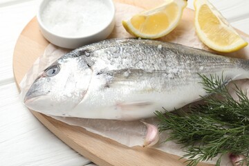Fresh raw dourade with spices on white wooden table, closeup. Fish and seafood delicacies