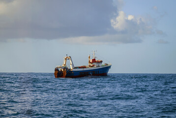 Fishing vessel is conducting an industrial catch of wild marine products using deep-sea trawl.