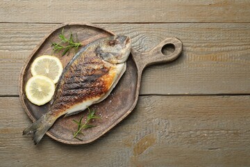 Homemade seafood dish. Tasty roasted dorado fish and spices on wooden table, top view. Space for text