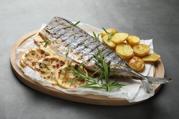 Tasty roasted mackerel with spices and potatoes on grey table, closeup. Homemade seafood dish