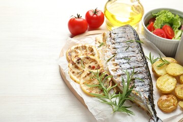 Homemade seafood dish. Tasty roasted mackerel served with potatoes and salad on light wooden table,...