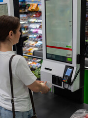 A woman scans items at a self-checkout. 