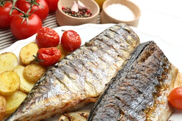 Tasty roasted mackerels with spices, tomatoes and potatoes on table, closeup. Homemade seafood dish