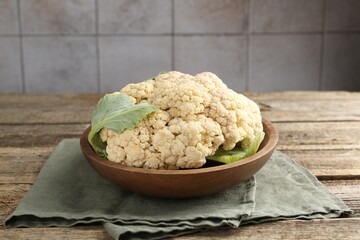 Fresh cauliflower with green leaves on wooden table, closeup