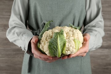 Woman with whole cauliflower on wooden background, closeup