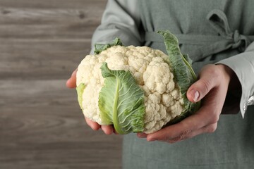 Woman with whole cauliflower on wooden background, closeup