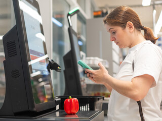 A woman buys bell peppers at a self-checkout. 