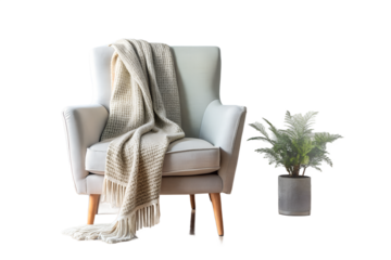 A white armchair with a throw blanket and a potted plant against black backdrop