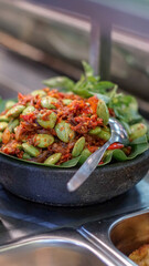 Spicy sambal with petai beans served in a traditional stone mortar. Authentic Indonesian dish full of flavor and heat, perfect for Asian food themes.