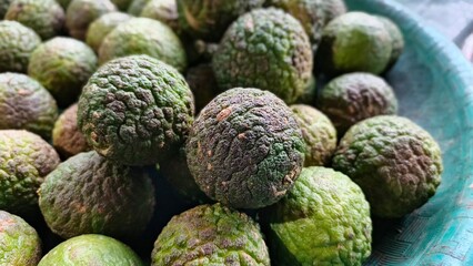 A heap of bumpy, green Kaffir limes are piled closely together, showcasing their textured skin.