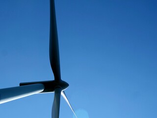White wind power generator against blue sky. Renewable clean energy.