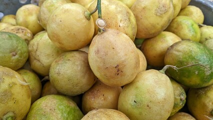 A close-up captures a pile of lemons, showcasing their yellow and green hues. The lemons have a round shape and a slightly textured surface, creating a fresh and zesty display.