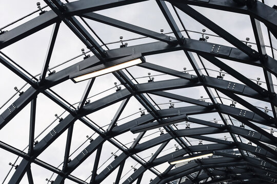 Modern steel glass structure. Architectural ceiling detail with geometric metal frames. Industrial design with glass panels and lighting. Urban infrastructure roof of contemporary public space.