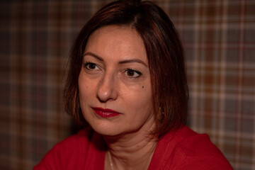 Mature caucasian woman with red lipstick and brown hair against plaid background