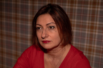 Mature caucasian female with short hair in red outfit against plaid background
