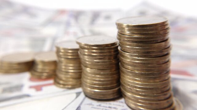 A stack of coins neatly arranged on top of scattered dollar bills, symbolizing wealth, savings, and financial growth.