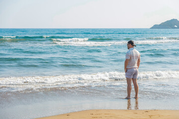 The man stands facing the sea and looks into the distance.