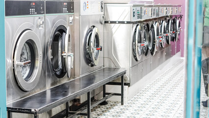 Urban laundry room with aligned washers in bright space and tiled wall interior