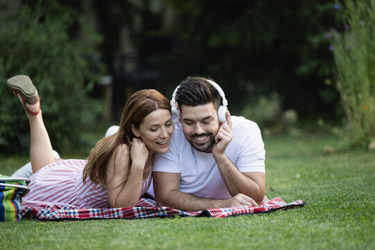 Couple listening to music while laying on blanket in park