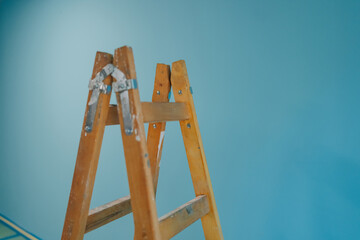 Wooden stepladder leaning against freshly painted blue wall during home renovation