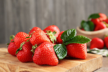 Delicious ripe strawberries and green leaves on table, closeup