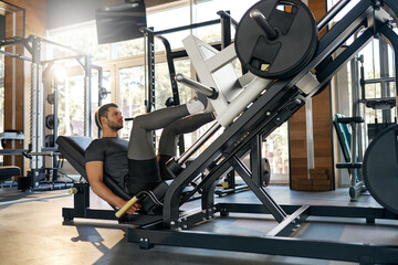 Fit man doing leg press exercise in modern gym. Focused on strength and lower body muscle building. Concept: power, discipline, training, fitness routine.