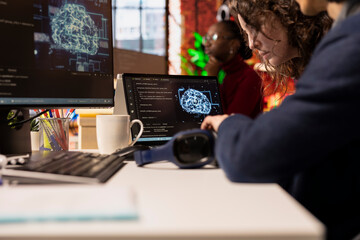IT engineers cooperating in AI focused startup overseeing worker designing, coding and debugging...