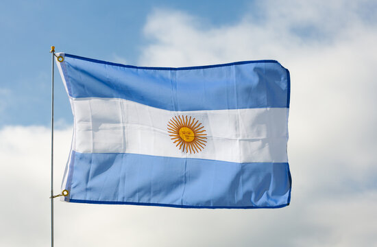 Big flag of Argentina fastened on stick against background of blue cloudy sky under daylight