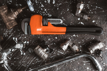Plumbing tools and accessories on black background. Top view with copy space.