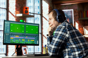 Video editor analyzing film montage on green screen computer monitor before editing color grading...